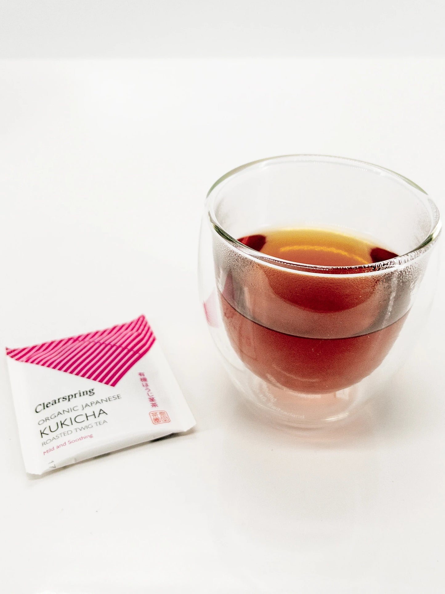 Verre de thé Kukicha bio Clearspring infusé, avec un sachet de thé à côté